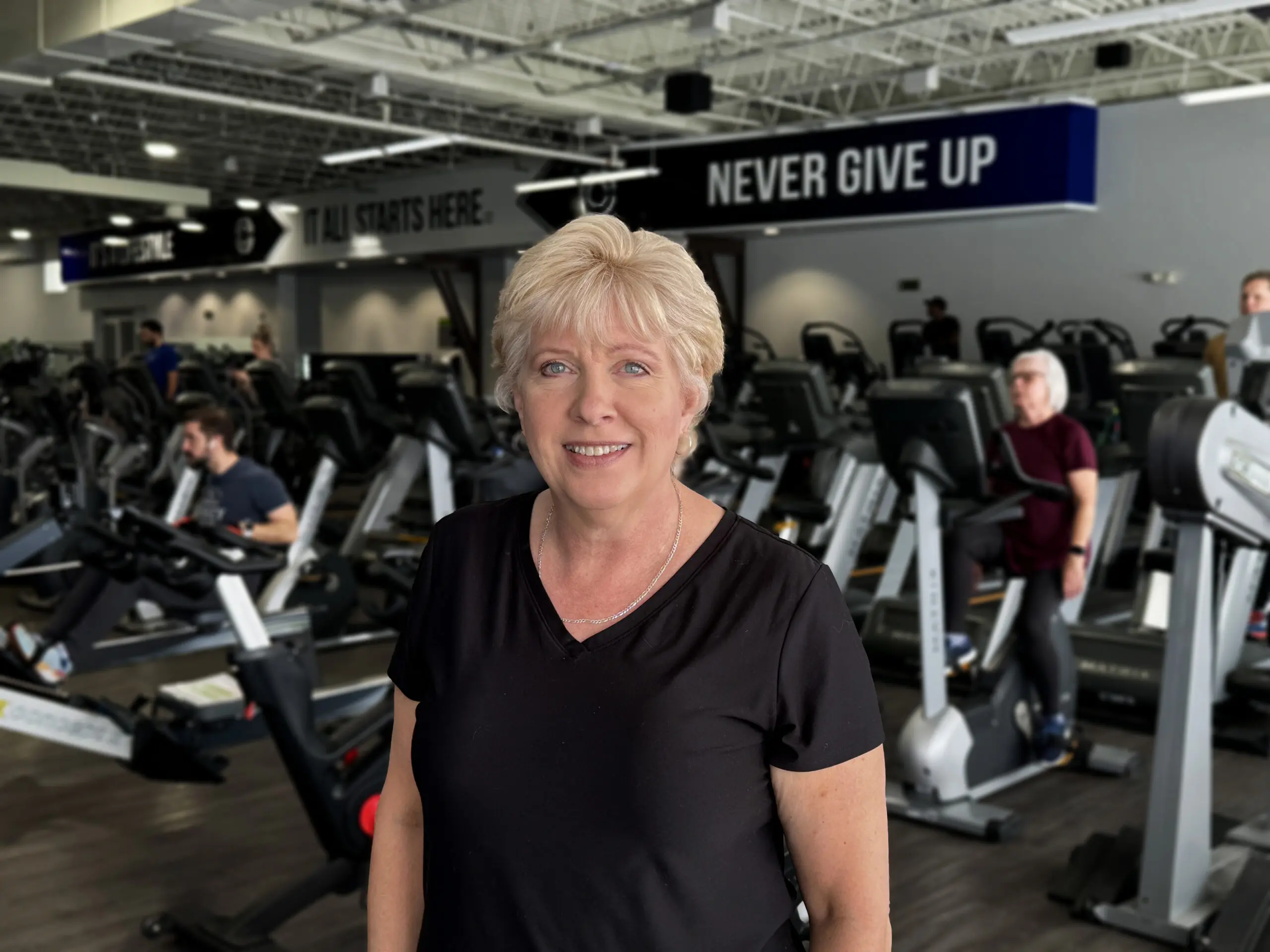 Amy Licata standing in the gym, smiling confidently after a workout at Catalyst Fitness, showcasing her 40-pound weight loss and dedication to personal training.