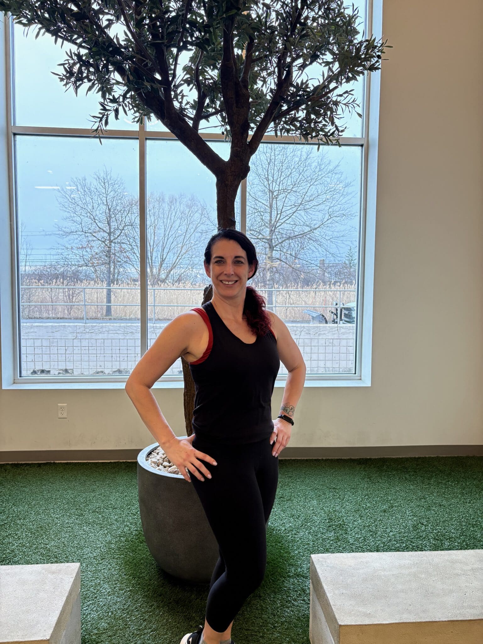 Women standing and smiling with her hands on her hips.