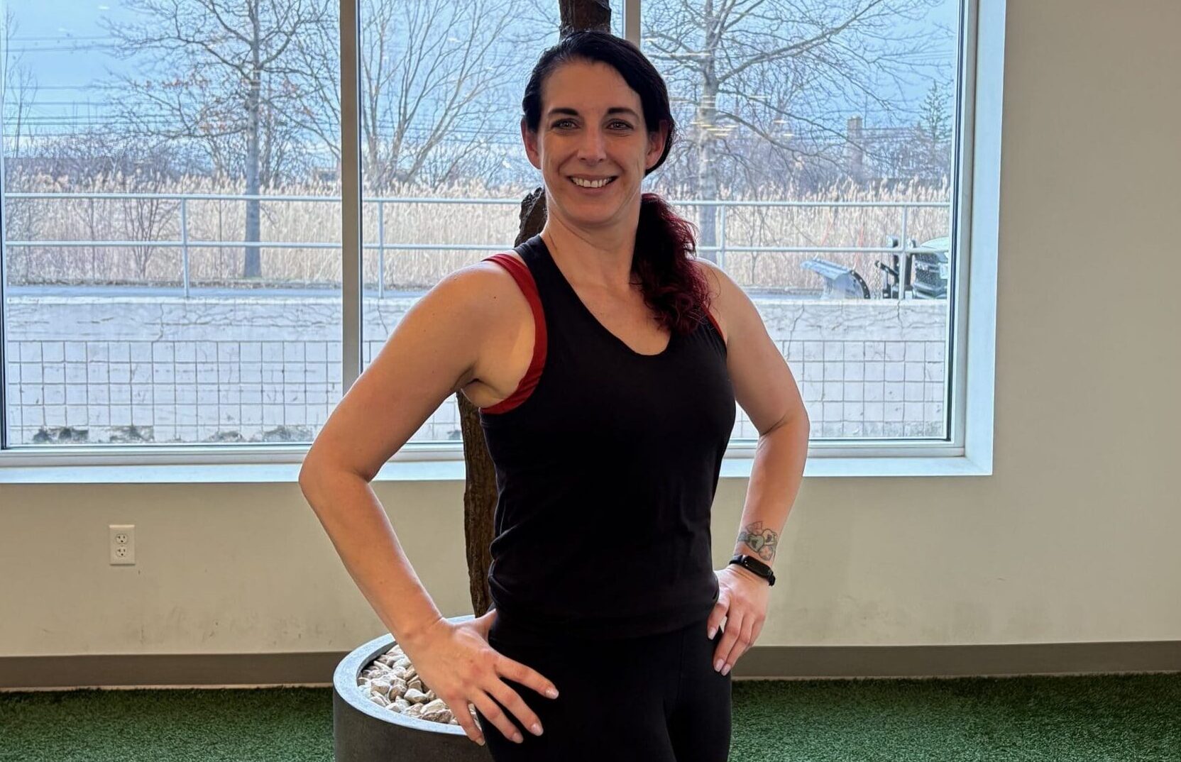 Women standing and smiling with her hands on her hips.